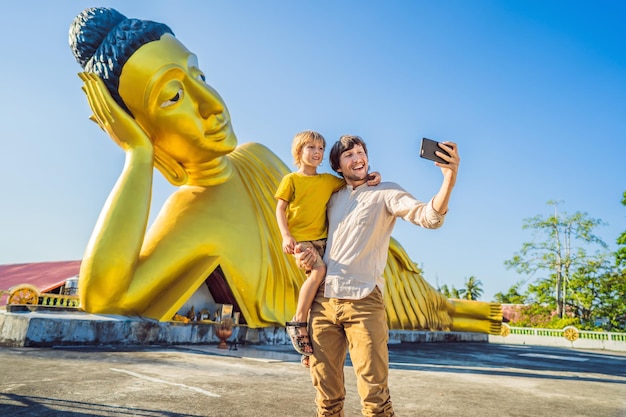 Turistas felices papá e hijo en el fondo de la estatua de Buda mentirosa