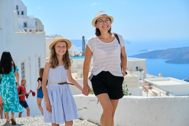 Turistas felizes família mãe e filha criança andando na ilha grega de Santorini. Cenário marinho cênico e paisagem arquitetônica tradicional