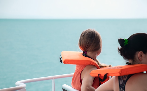 Los turistas llevan chalecos salvavidas sentados en el barco.