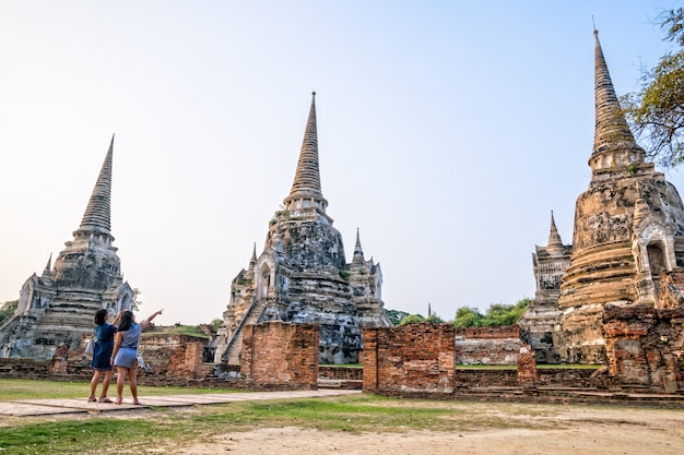 Turistas, mãe e filha, fotografam ruínas antigas e pagode das atrações famosas do Templo Wat Phra Si Sanphet no Parque Histórico Phra Nakhon Si Ayutthaya, na província de Ayutthaya, Tailândia