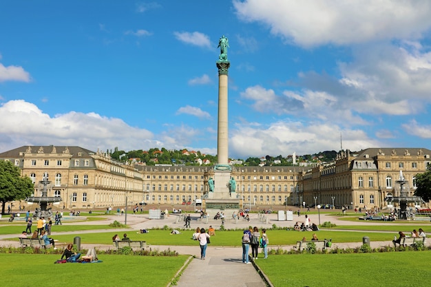 Foto turistas na schlossplatz com coluna e o novo palácio em stuttgart, alemanha