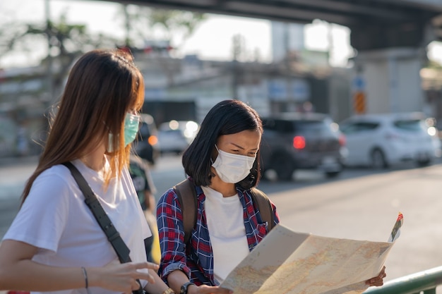 Turistas niñas con máscaras faciales ar street. las mujeres viajan durante la cuarentena por coronavirus.