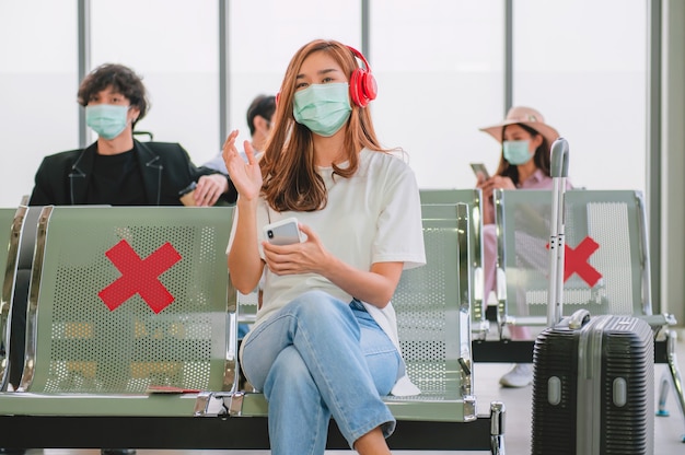 Turistas ouvem música e usam máscaras para evitar vírus enquanto esperam para embarcar no avião