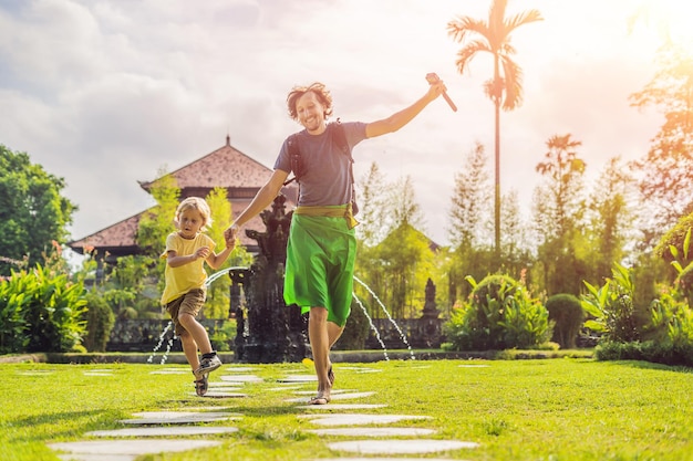 Turistas de papá e hijo en el templo hindú tradicional balinés Taman Ayun en Mengwi. Bali, Indonesia. Concepto de viajar con niños. con la luz del sol