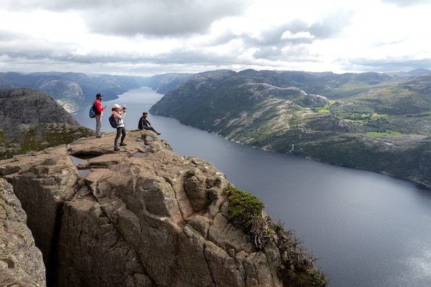 Los turistas se paran al borde de la roca y admiran el paisaje.