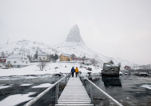 Turistas de pie en el puente de madera con nieve