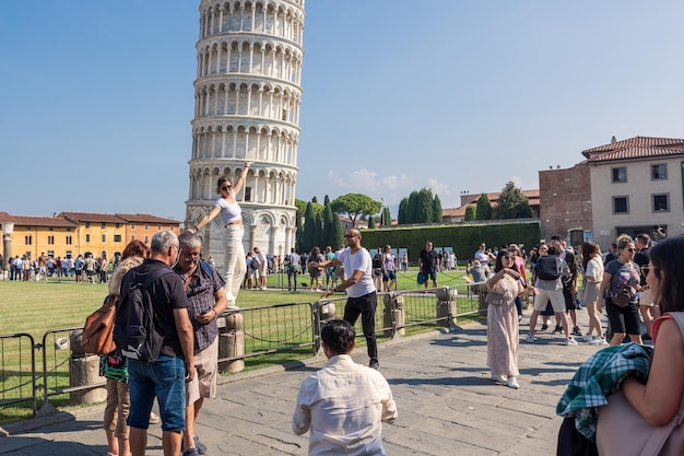 Turistas posando na Piazza del Duomo com a Torre Inclinada em um dia ensolarado em Pisa, Itália