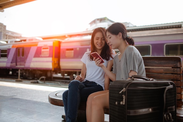 Los turistas que viajan usan teléfonos inteligentes en una estación de tren