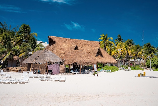Turistas relajarse y tomar el sol bajo un dosel de paja en la playa durante las vacaciones de verano. Resort de playa en un día soleado
