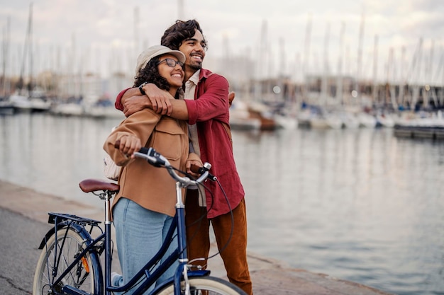 Turistas românticos com bicicleta estão se abraçando no cais e apreciando a vista