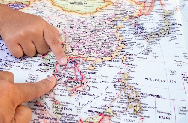 Los turistas señalan con la mano el mapa mundial de Tailandia Situado en el sudeste asiático, Tailandia es una capital cultural de interés mundial y un destino vista de arriba