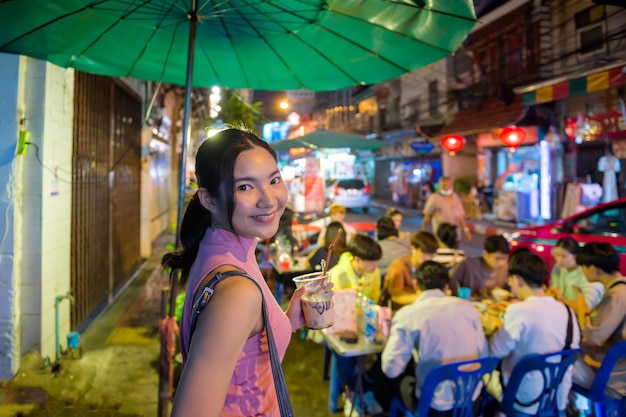 Turistas tailandeses-chineses passeiam e experimentam comida de rua em Yaowarat Road, Chinatown, Bangkok