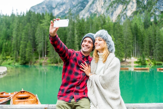 Foto turistas tomando selfie visitando un lago alpino