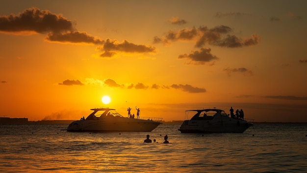 Los turistas en yates se encuentran con la puesta de sol en el Mar Caribe cerca de Isla Mujeres México