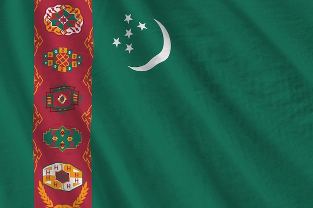 Turkmenistan-Flagge mit großen Falten, die unter dem Studiolicht im Innenbereich die offiziellen Symbole wehen
