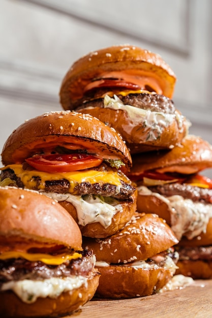 Turm aus Burgern mit marmoriertem Rindfleisch, eingelegten Gurken, Cheddar-Käse, Tomaten, karamellisierter Zwiebel-Tartar-Sauce