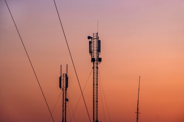Turm mit mobilem 5G-Signalsender vor dem Hintergrund des orangefarbenen Himmels