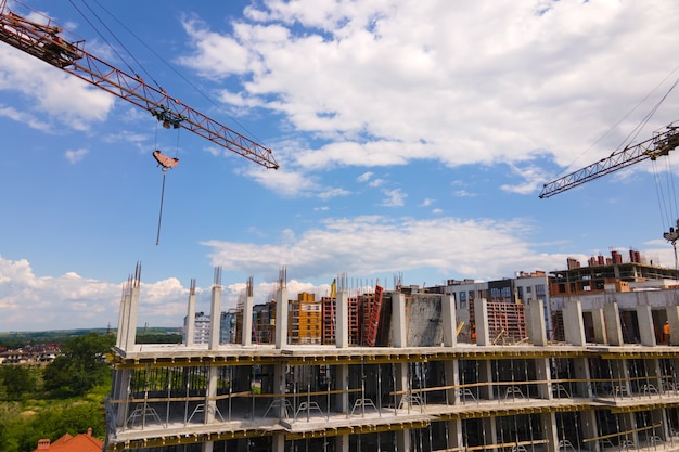 Turmdrehkran am hohen Betonwohngebäude im Bau. Immobilienentwicklungskonzept.