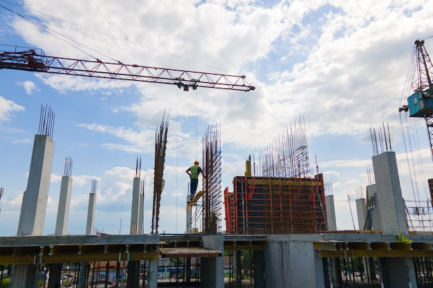 Turmdrehkran am hohen Betonwohngebäude im Bau. Immobilienentwicklungskonzept.