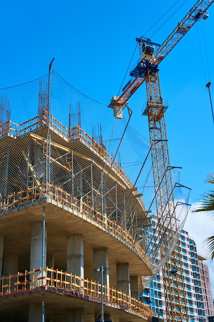 Turmdrehkran auf der Baustelle eines modernen Gebäudes nahe dem Meer.