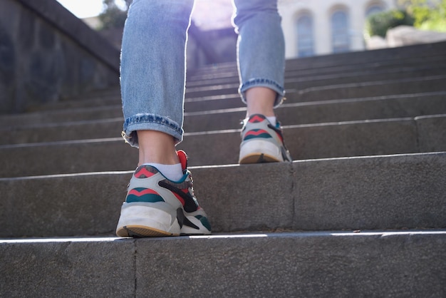 Turnschuhe der jungen Frau klettern Treppen in modernen Stadtkämpfen oder Sportwanderkonzepten