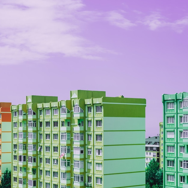 Turquesa verde y parte de las casas de arquitectura de construcción de paneles naranjas sobre fondo de cielo púrpura Casas residenciales urbanas antiguas de nueve pisos con ventanas