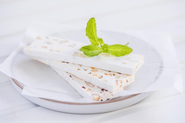 Turrón blanco en rodajas con almendras sobre mesa de madera