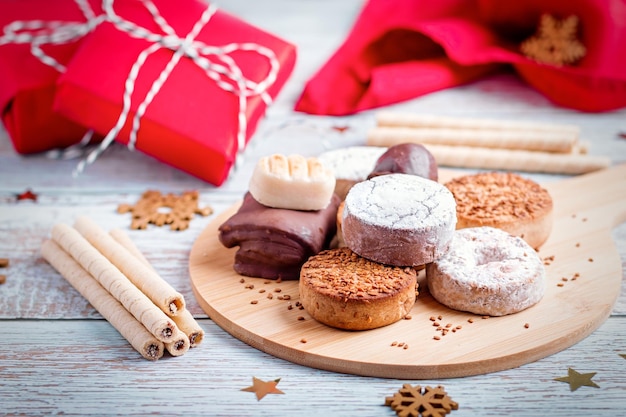 Foto turrón de dulces navideños tradicionales españoles, polvorones, mantecados con decoración navideña y cajas de regalo rojas en la mesa de madera clara, espacio de copia