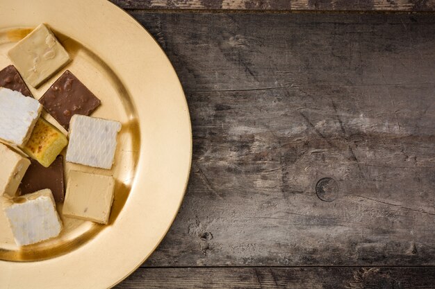 Foto turrón de navidad en una placa de oro sobre mesa de madera.