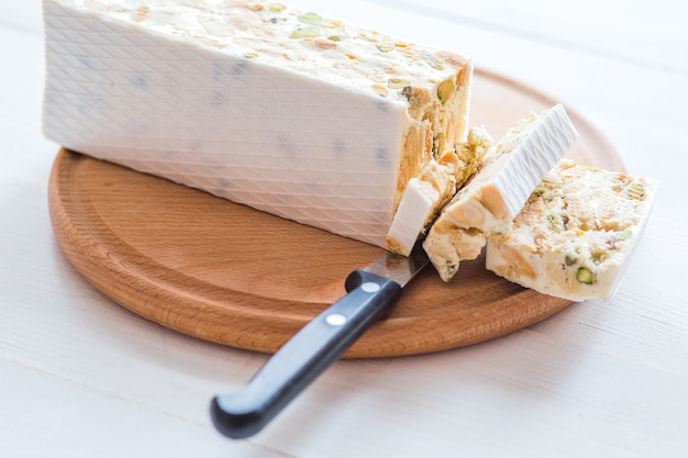 Turrón o turrón italiano con almendras sobre una mesa de madera blanca, cerrar con el enfoque seleccionado, cerrar