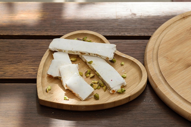 Turrón con pistachos en un plato en forma de corazón. Estar iluminado por un rayo de sol.