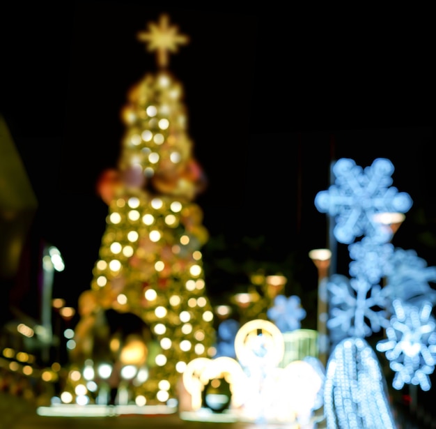 Turva e bokeh a vista da árvore de natal e decorar a iluminação led na frente do shopping na noite de natal na cidade urbana.