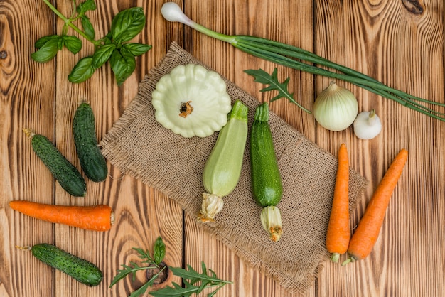 Tutano vegetal fresco, pepinos, cenouras e verdes em um fundo de madeira
