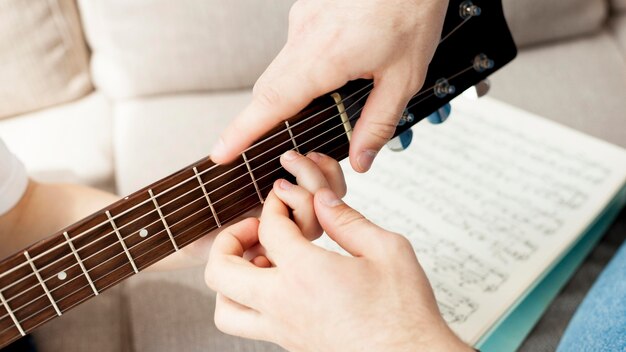 Foto tutor de close-up, aprendendo o menino como tocar violão