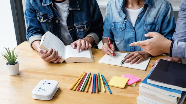 Tutor do ensino médio ou grupo de estudantes universitários sentado na mesa na biblioteca, estudando e lendo, fazendo lição de casa e prática de aula, preparando o exame para entrada, educação, ensino, conceito de aprendizagem