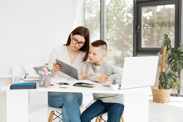 Tutor e menino aprendendo em casa