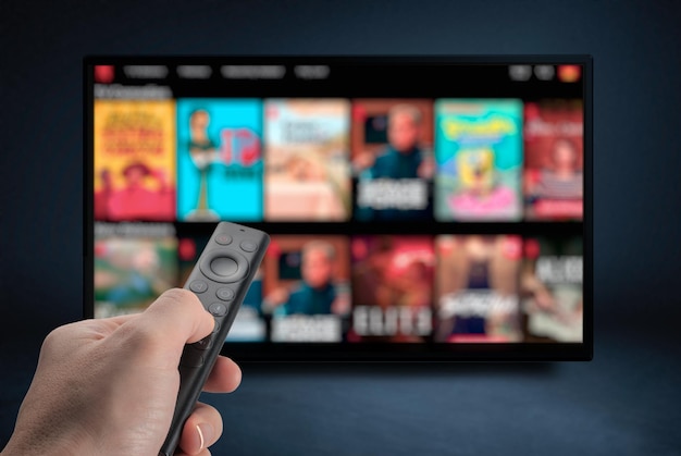 Foto tv online tv-streaming-video männliche hand mit tv-fernbedienung multimedia-streaming-konzept anbieter von vod-inhalten videodienst mit internet-streaming-multimedia-shows-serien