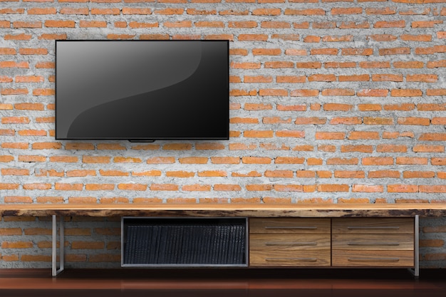 Foto tv en pared de ladrillo rojo con mesa de madera vacía media muebles en la sala de estar