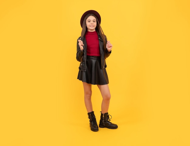 Tween fashion look infância felicidade garota feliz em couro usa alegre e elegante criança adolescente de chapéu em fundo amarelo tendências da temporada outono caem moda sazonal de volta à escola