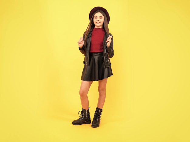 Tween fashion look infância felicidade garota feliz em couro usa alegre e elegante criança adolescente de chapéu em fundo amarelo tendências da temporada outono caem moda sazonal de volta à escola