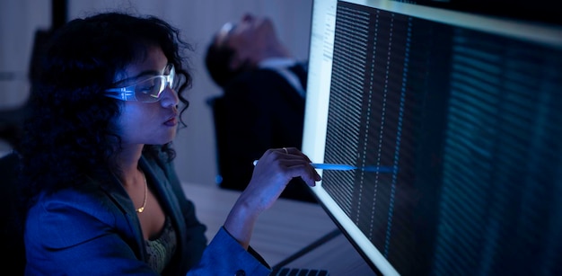 Two software developers collaborating at night focusing on code review and debugging process on a computer screen representing teamwork innovation and modern software development workflow