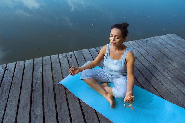 Tyoung Frau, die Yoga am See tut