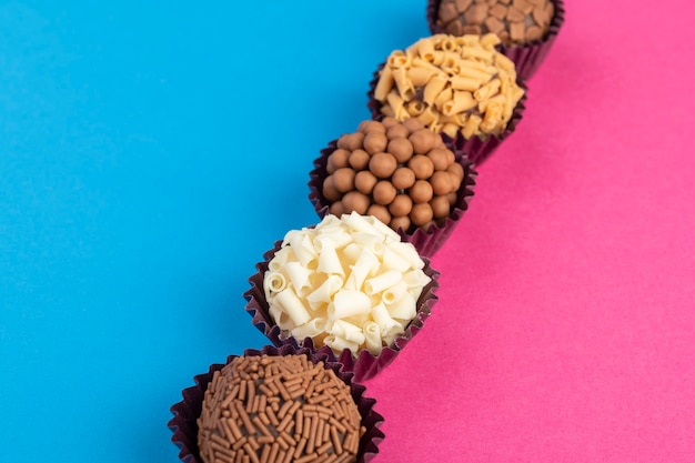 Typische brasilianische Brigadeiros, verschiedene Geschmacksrichtungen über buntem Hintergrund