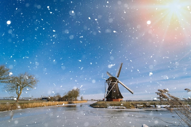 Typische holländische Winterlandschaft mit gefrorenem Kanal der Windmühle im traditionellen Winterholland der Niederlande