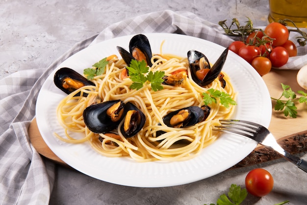 Typische italienische Pasta-Spaghetti mit Muschel und Tomaten auf einem weißen Teller