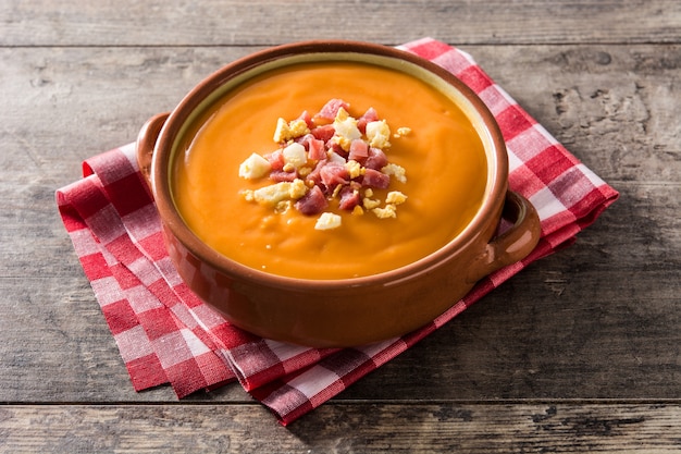 Typische spanische Salmorejo-Creme mit Schinken und Ei auf Holztisch