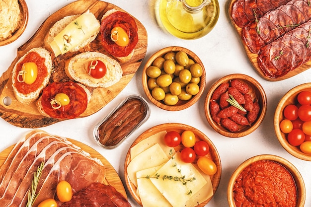 Typisches spanisches Tapas-Konzept. Das Konzept umfasst Scheiben Jamon, Chorizo, Wurst, Schalen mit Oliven, Tomaten, Sardellen, Kichererbsenpüree, Käse.