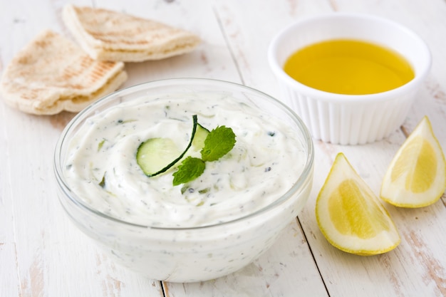 Tzatziki e ingredientes en la mesa de madera blanca