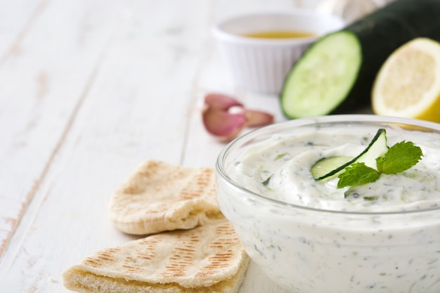 Tzatziki e ingredientes en la mesa de madera blanca