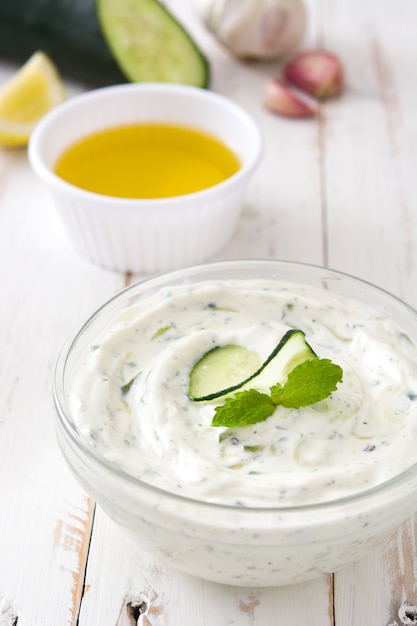 Tzatziki e ingredientes na mesa de madeira branca